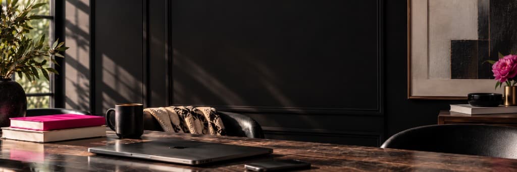 Dark wood desk with laptop, books, and pink peony in a moody home office